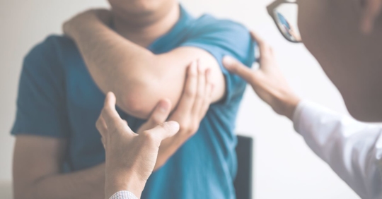 man holding elbow during doctor exam